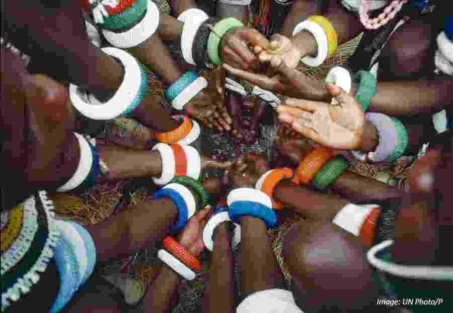 A top-down view of the arms of young men of the Ndebele tribe of South Africa, adorned with colourful beaded bracelets and bands and clustered together 